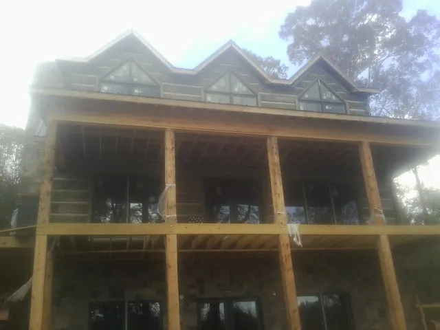 Dormers and porch framing on a large log home under construction — Roof Coating work by our crew in Mc Cormick