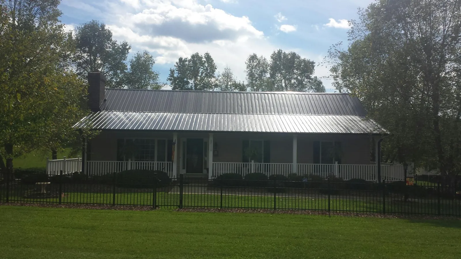 Gray metal roof on a brick ranch with a full width front porch — Gutter Guard Installation work by our crew in Mc Cormick