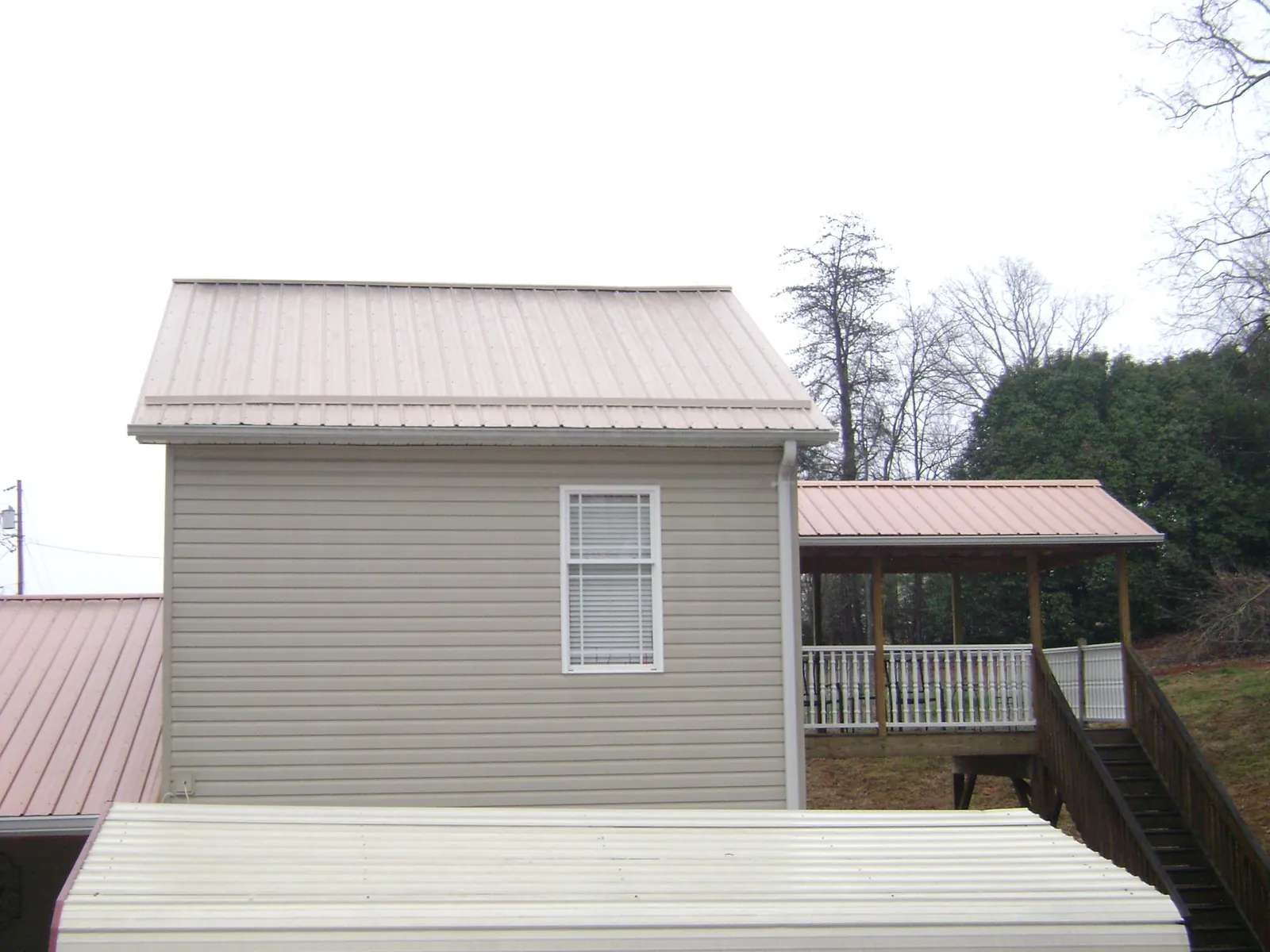 Tan metal roofs on a two story addition and attached porch, from a Roof Replacement job in Mc Cormick