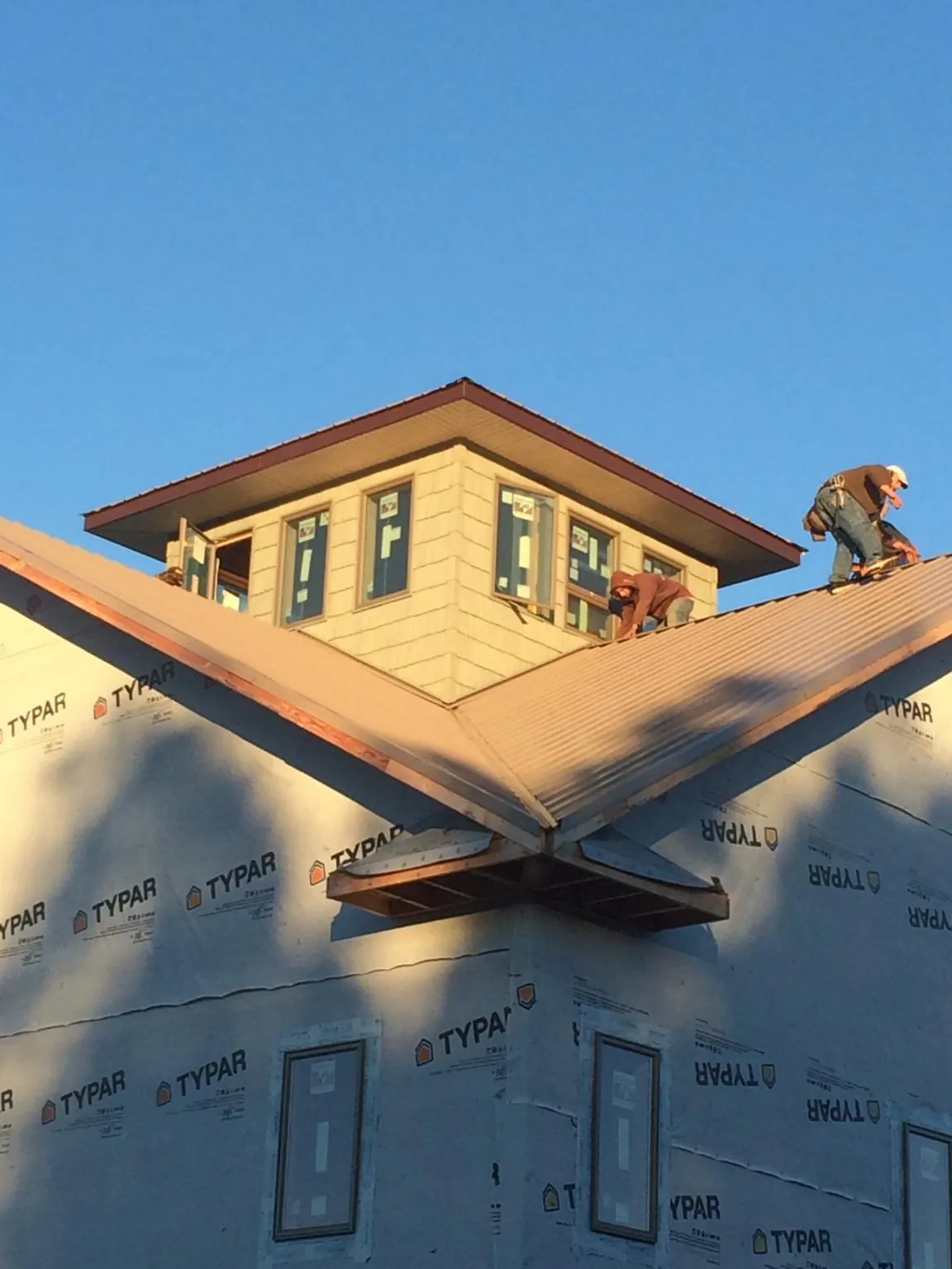 Roofers working around a rooftop cupola on a new metal roof at sunset — Roof Waterproofing in Mc Cormick by Roofing Brothers